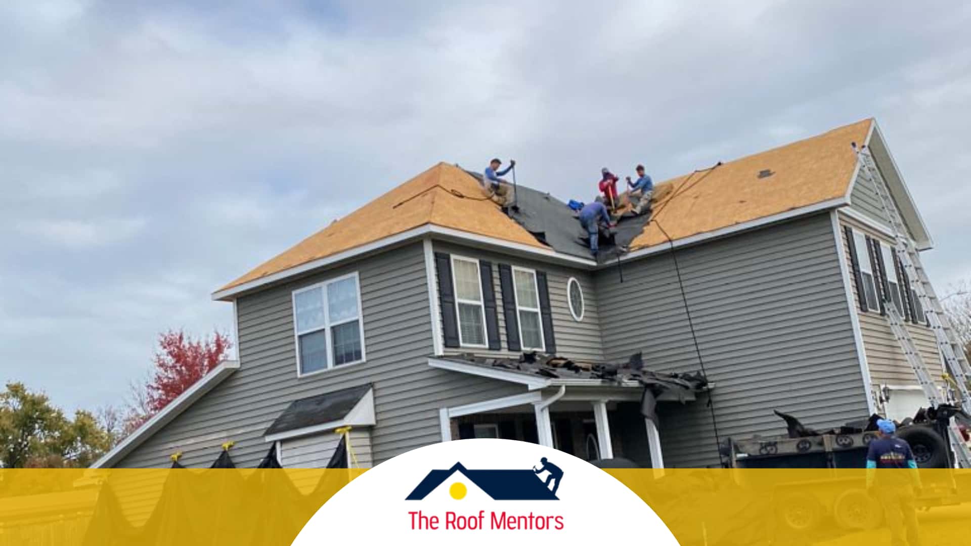 A group of roofing contractors are working on the roof of a house.