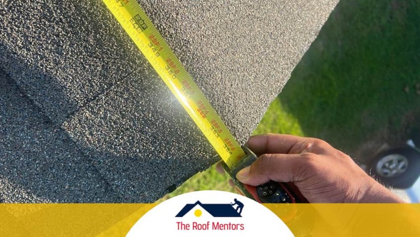 A person measuring a shingled roof with a tape measure.